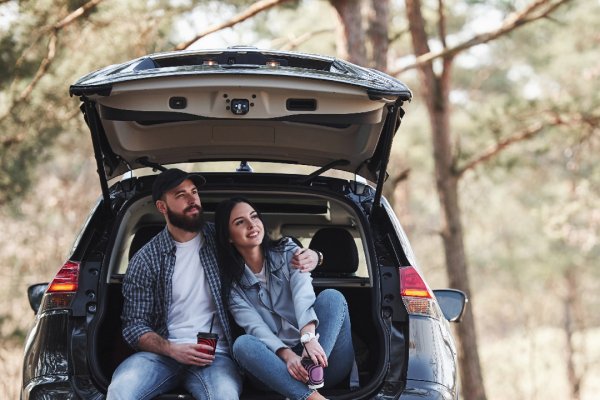 Couple sitting in the boot of their new car Couple sitting in the boot of their new car