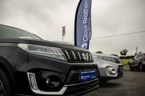 Image of a black car with a Close Brother Motor Finance car reg and flag behind
